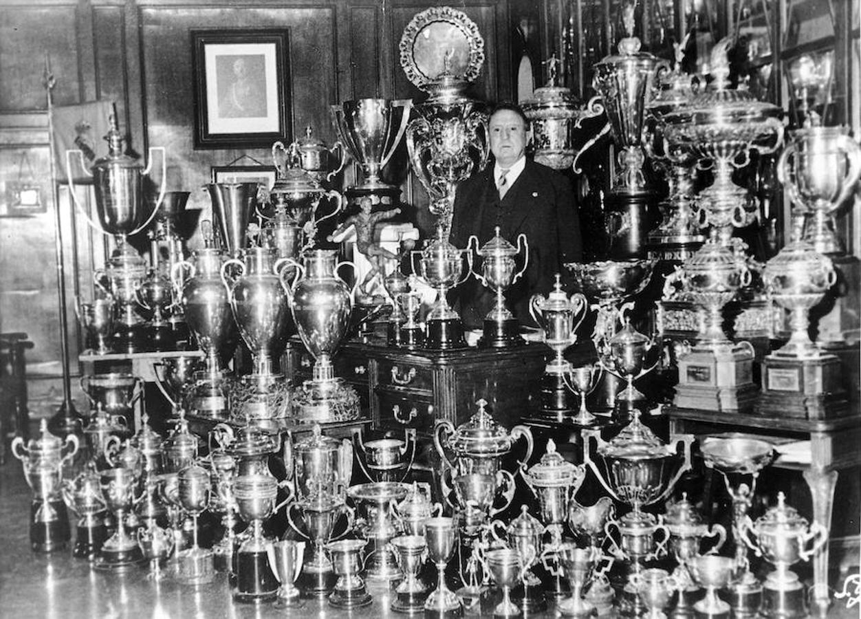 El presidente del Real Madrid, Santiago Bernabéu, con posando con todos los trofeos del club. 