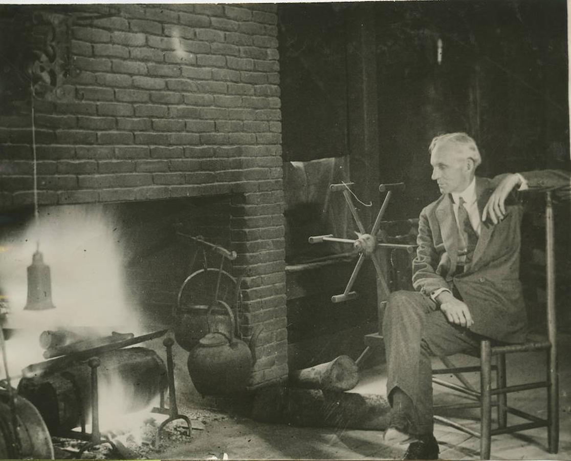 Henry Ford sentado delante de una antigua chimenea en la taberna que adquirió en Clarenceville.. 