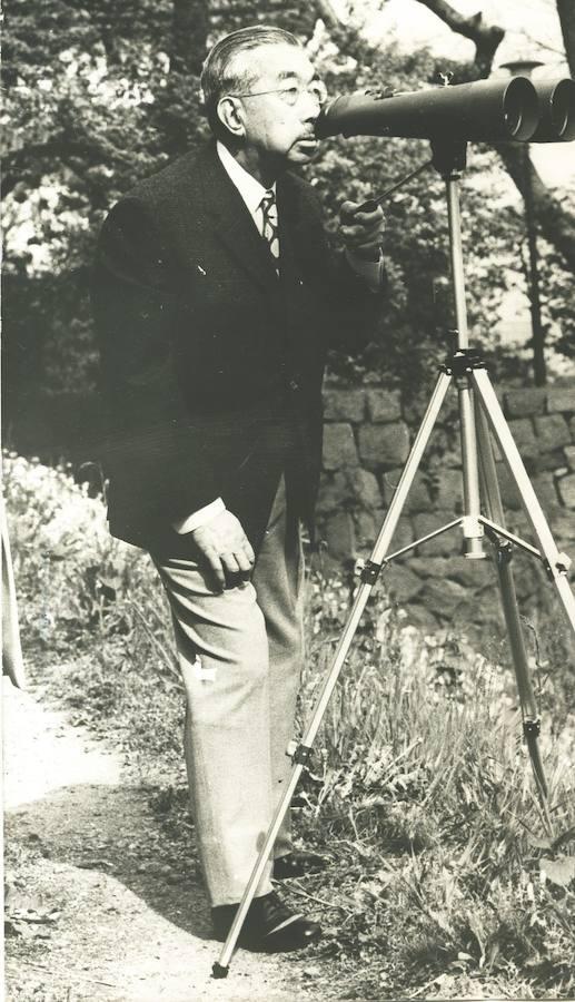 Hiro Hito observando aves con unos prismáticos en los jardínes imperiales. 