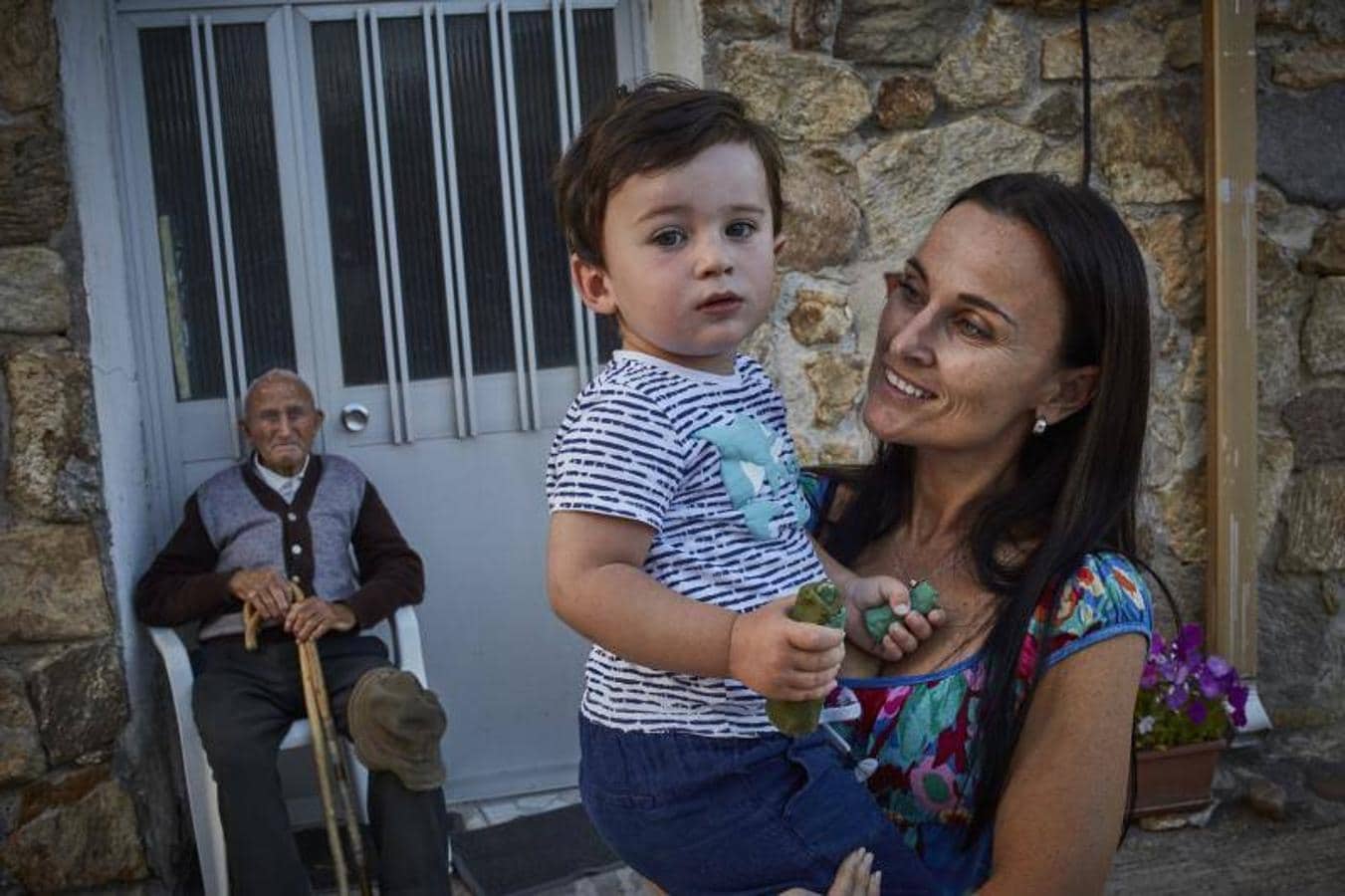 1. Ana sostiene en brazos a su hijo Daniel, de 2 años, con Pedro, de 100, detrás de ellos; son el más joven y el más viejo de Piñuécar