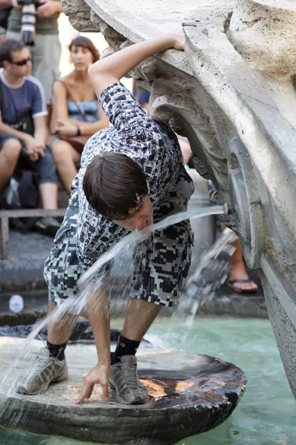 Los turistas se hidratan en las fuentes de Italia. Un joven bebe agua en la Fontana de la Barcaccia, una fuente de Pietro y Gian Lorenzo Bernini de 1627. Está ubicada ante la escalinata de la plaza de España de Roma, Italia.