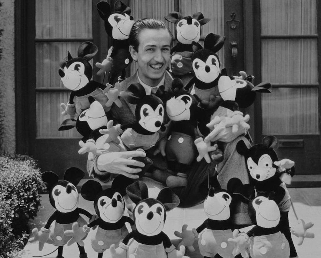 Walt Disney rodeado de muñecos de Mickey Mouse. 