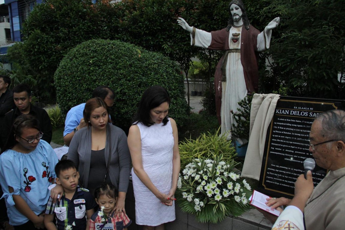 El obispo emérito de Caloocan, Deogazias Yniguez, descubre una placa en la catedral de San Roque en honor de Kian de los Santos, víctima colateral de la "guerra sucia" contra la droga, ante su familia y la senadora Risa Hontiveros (de blanco).. 