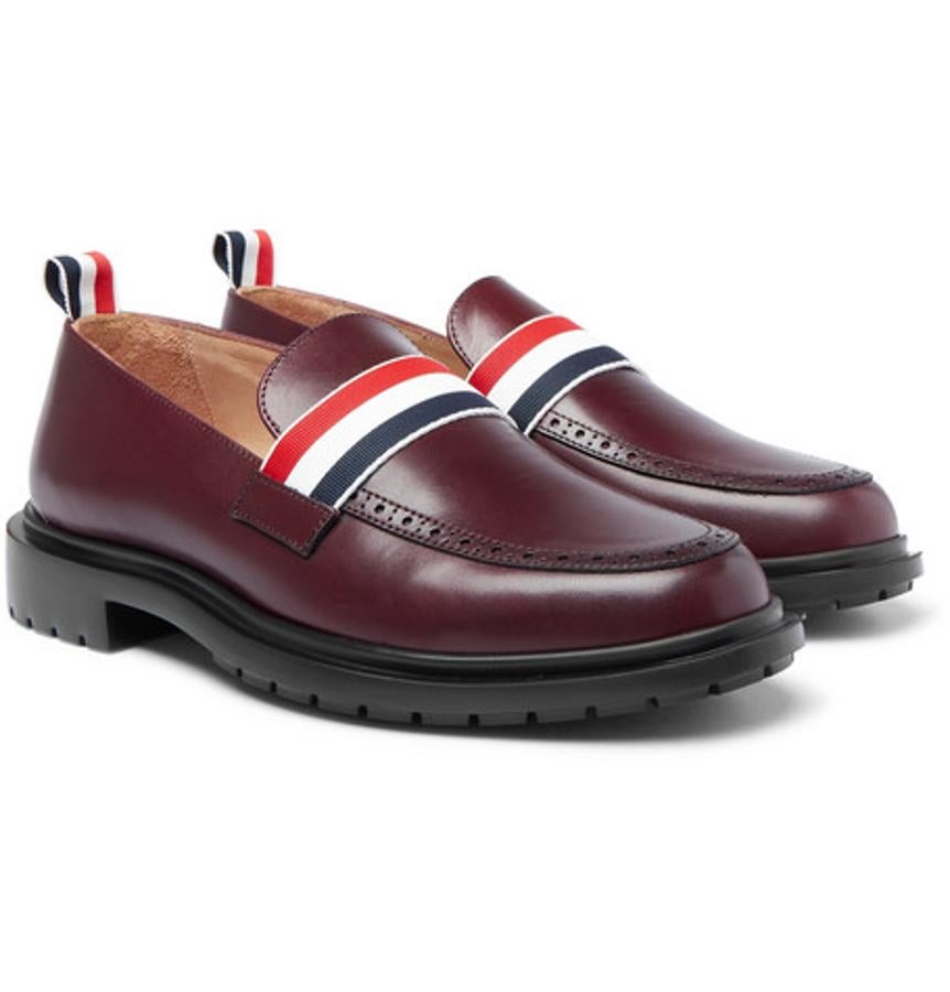 Mocasines de Thom Browne. Las rayas americanas tan características de Thom Browne llegan también a los mocasines para dar a este calzado clásico un aspecto menos serio. Fabricado en Italia en cuero marrón y rematado con suela de goma. Perfectos para lucirlos con calcetines recortados. Precio: 860 euros.