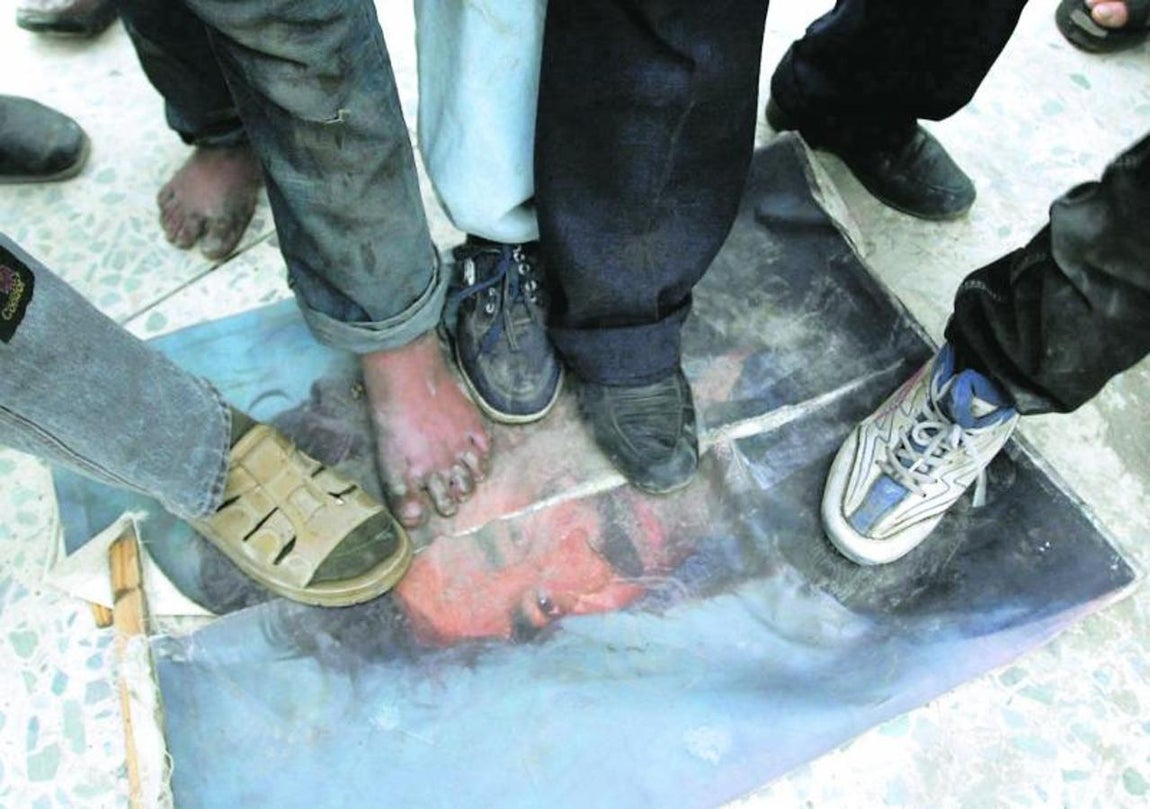 Varios iraquíes pisan un cartel con la imagen de Sadam. 