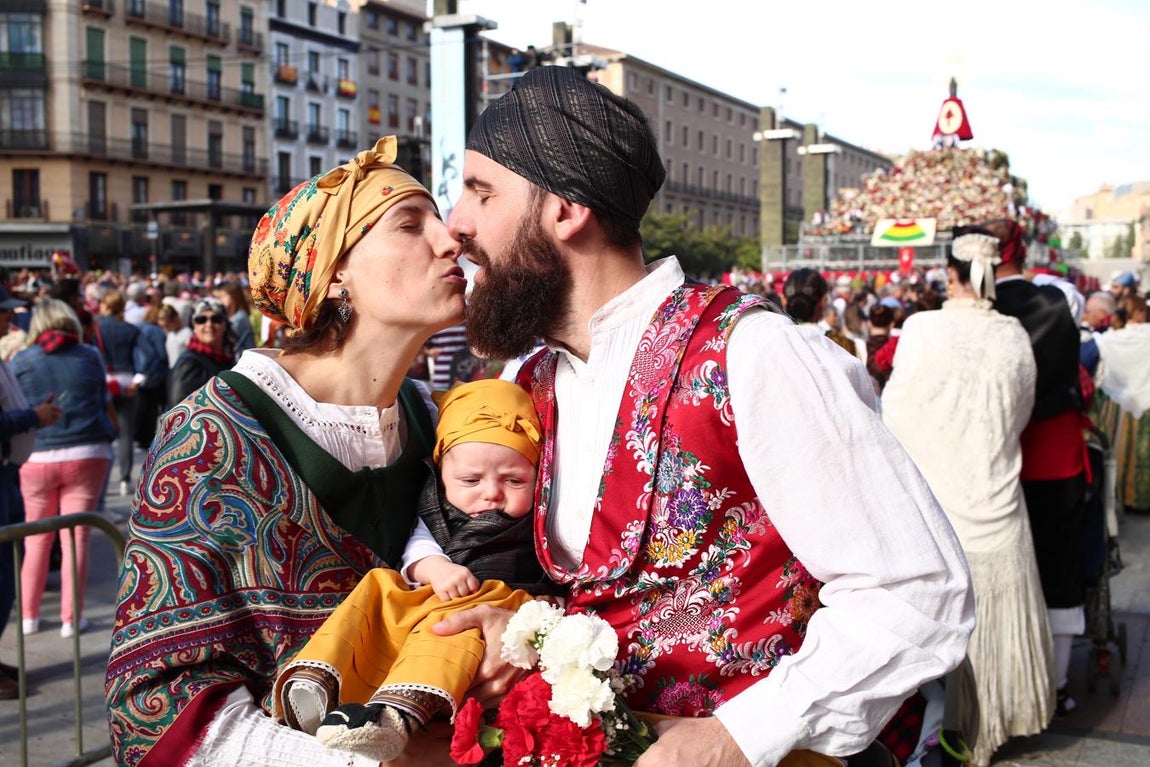 Tradición, en familia. Un joven matrimonio, con su bebé en brazos para llevar sus flores a la Virgen del Pilar. La participación de familias en la Ofrenda ha sido muy numerosa.