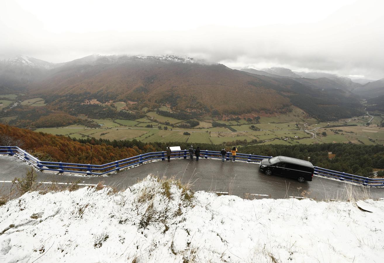 Un grupo de personas observan desde un mirador el valle de Belagoa (Navarra) cuyos bosques presentan los colores típicos del otoño y donde la nieve caída ha dejado una estampa invernal.. 