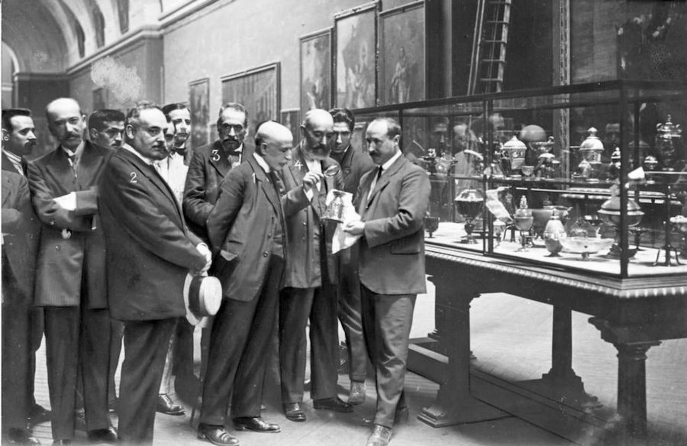 El inspector Aranda (4) inspecciona una pieza tras el robo del Tesoro del Delfín en 1918, ante la mirada del jefe de la brigada de investigación, Ramón Fernández Luna (3), el presidente de la audiencia, sr. Ortega Morejón (1) y el subdirector del museo, sr. Garnelo (2). 