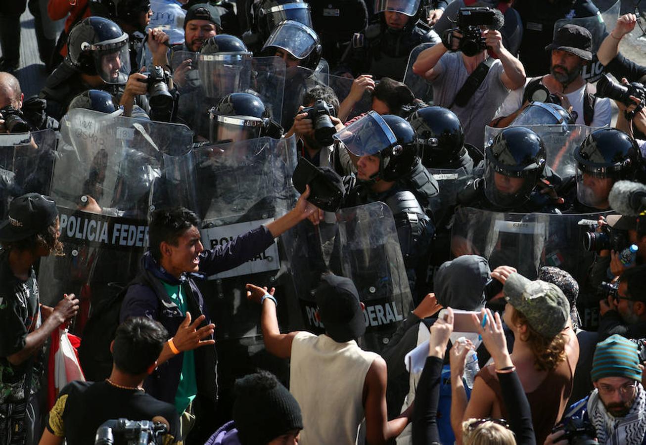 Cientos de inmigrantes tratan de cruzar por la fuerza la frontera entre México y EEUU. Los miembros de la caravana rompen el cerco policial y corren para intentar pasar a Estados Unidos