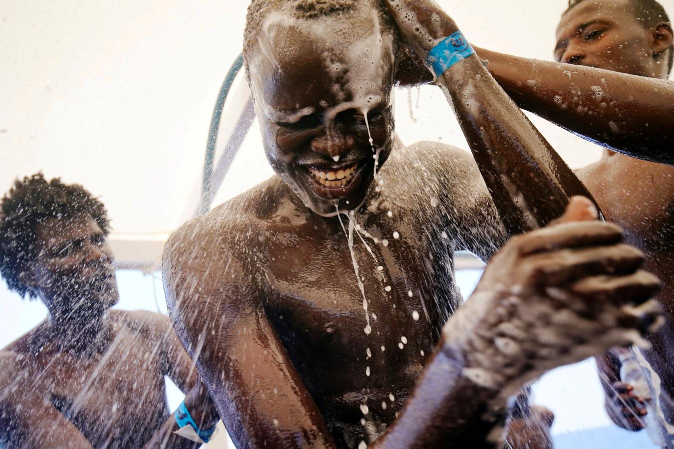 El sudanés Chuol, de 17 años, se toma una ducha a bordo del bote de rescate de la ONG española Proactiva Open Arms en el mar Mediterráneo central, el 3 de agosto de 2018.. 