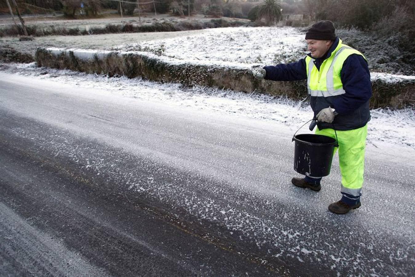 Un operario esparce sal en uno de los accesos a Leiro (Orense) con motivo de las bajas temperaturas nocturnas que están ocasionando importantes heladas en toda Galicia. 