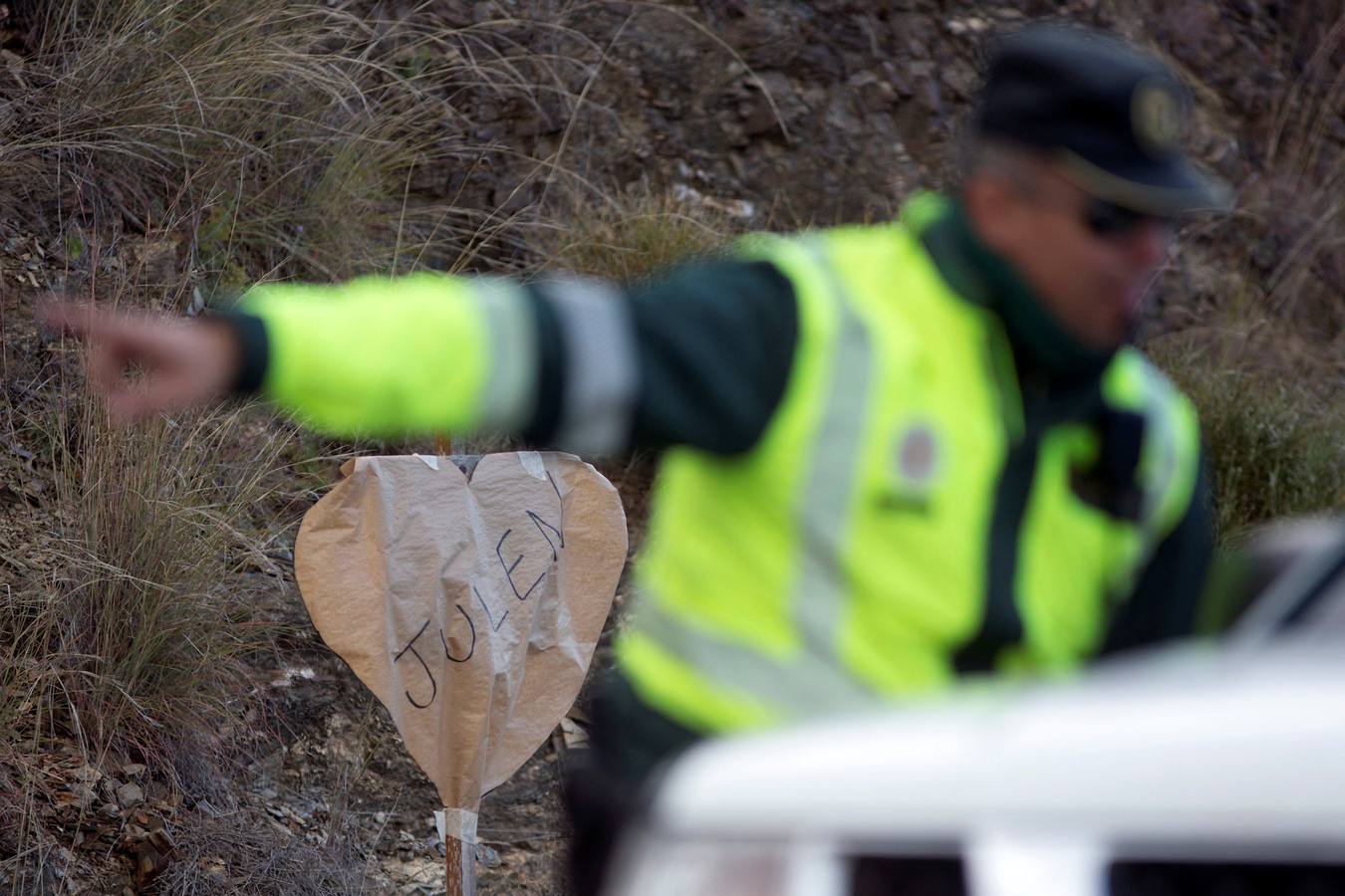 Un Guardia Civil hace indicaciones delante de un cartel con el nombre de Julen. 