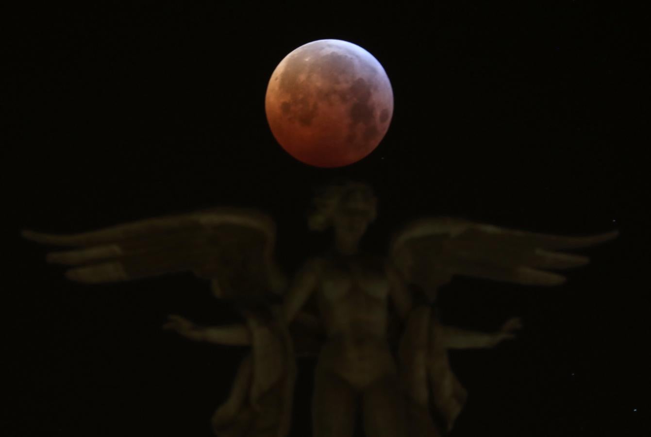 La superluna de sangre de lobo, vista sobre el edificio de «Metrópolis», en la esquina de las calles Alcalá y Gran Vía en Madrid. 