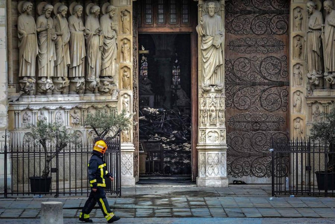 Un bombero observa el interior de la catedral, donde se observan escombros de piedra y madera. 