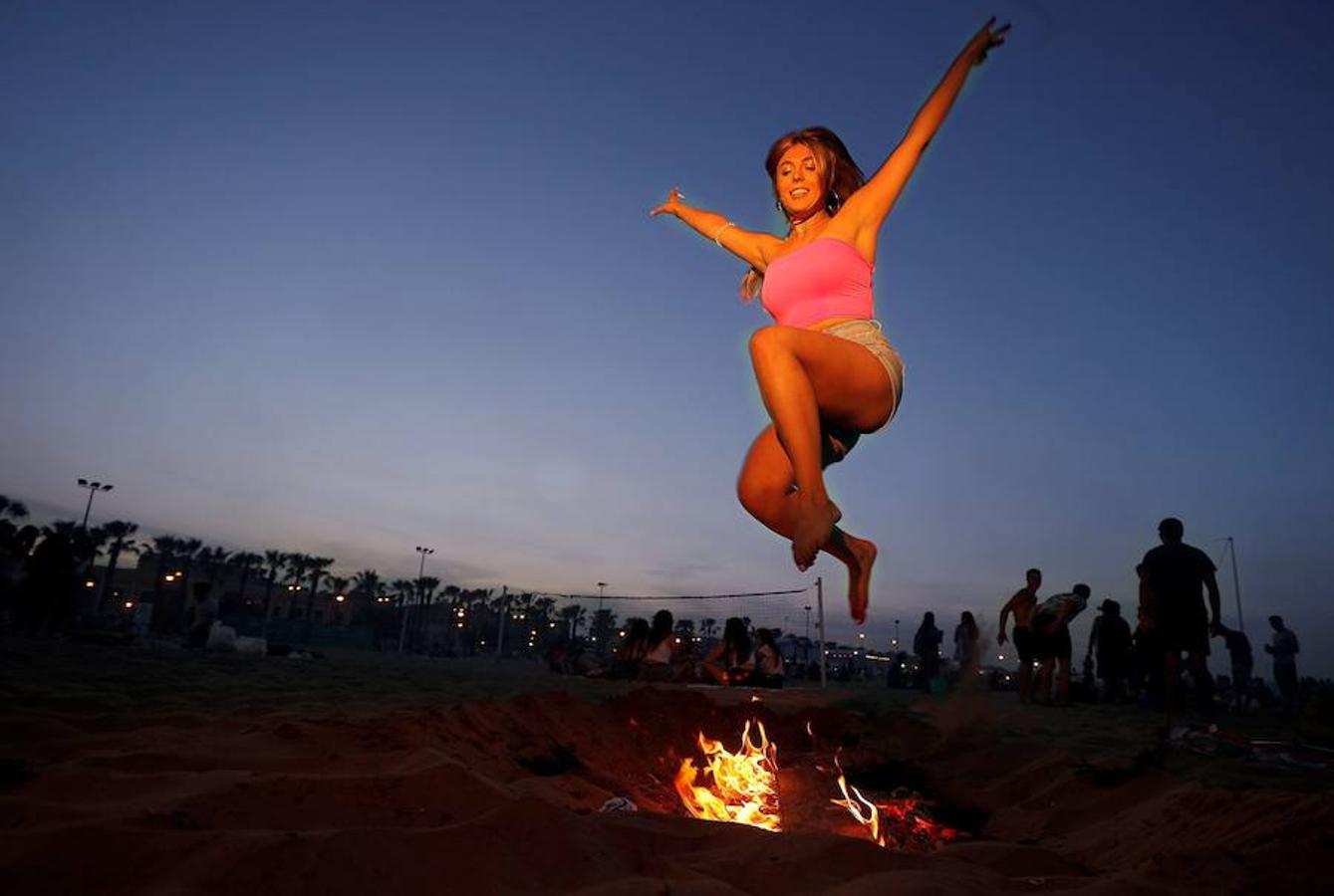 Una mujer salta sobre una hoguera para celebrar la noche de San Juan en la playa La Malvarrosa en Valencia. 