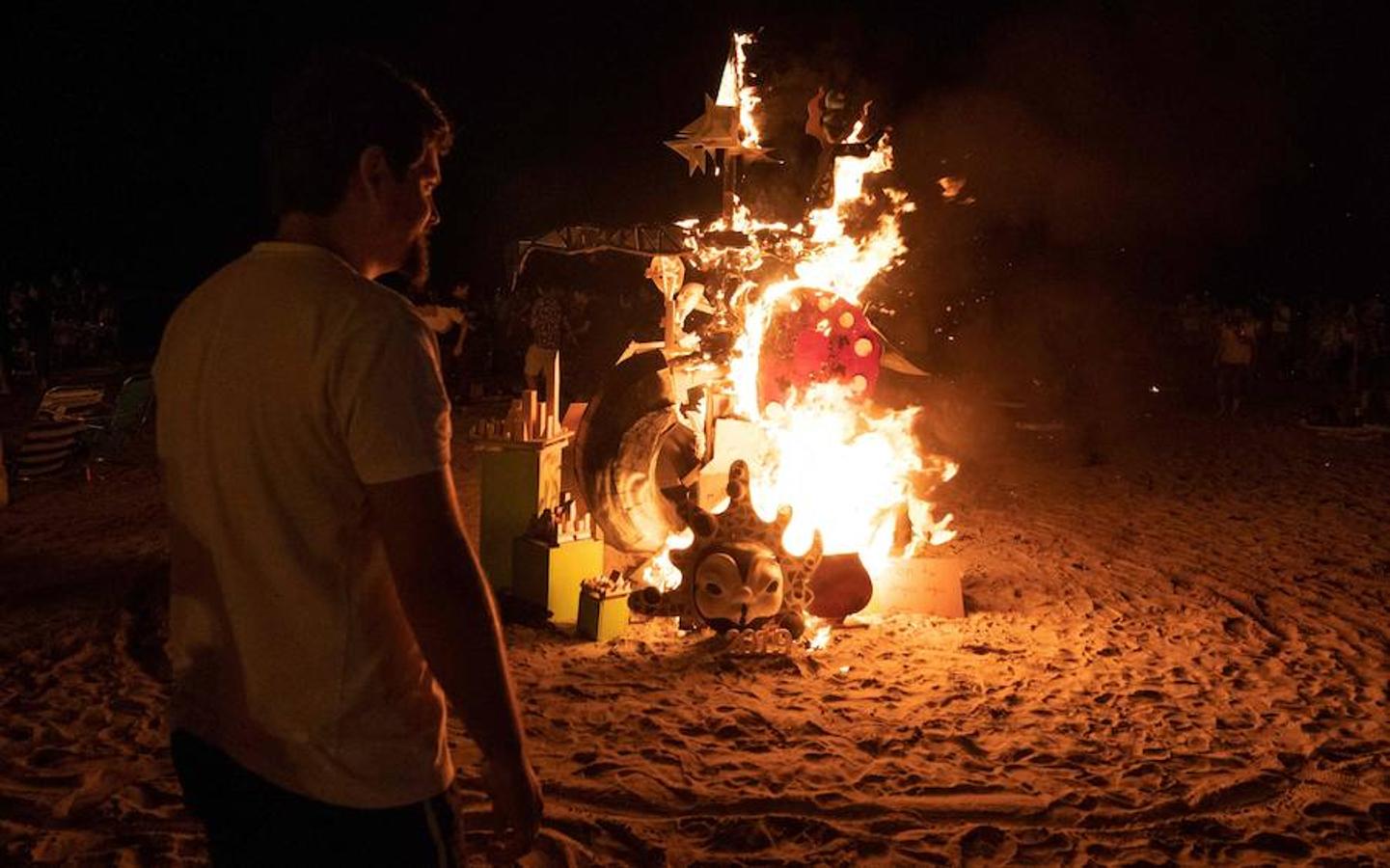 Un hombre observa la quema de una figura durante la noche de San Juan. 