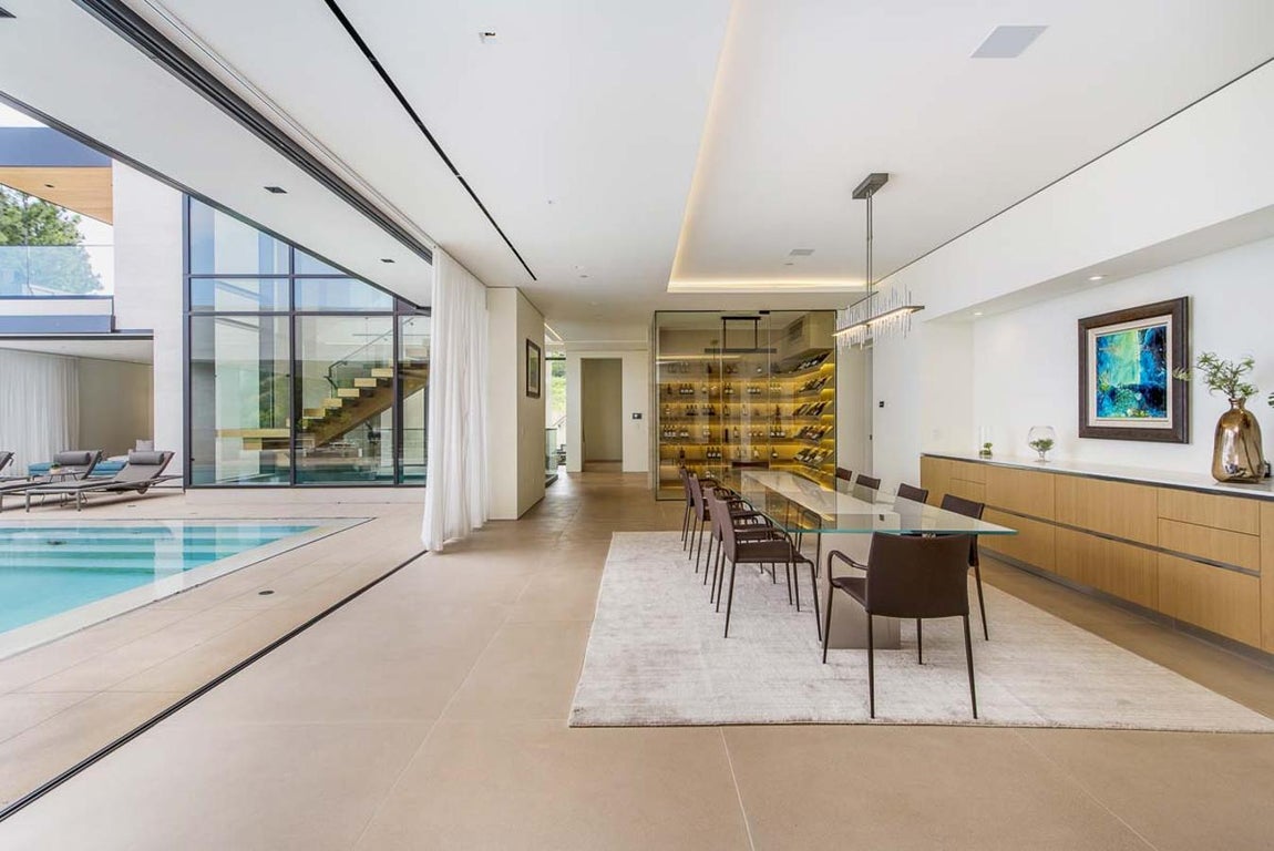 Hall. La vivienda, con decoración moderna e incluso puertas automáticas, ha sido hecha con colores neutros y enormes ventanales que permiten mayor luminosidad. Además, está distribuida en siete habitaciones, doce baños, cocina, comedor, varias salas de estar, un increíble patio con dos piscinas que por la noche lucen con colores llamativos, alguna que otra terraza y, por supuesto, brinda las mejores vistas del horizonte de Los Ángeles.