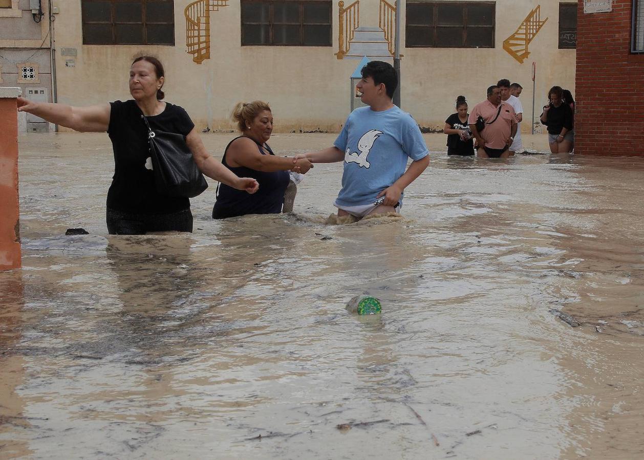 Varios vecinos tras inundarse las calles de la población por la rotura del dique del cauce del río Segura tras el paso de la Gota Fría. 