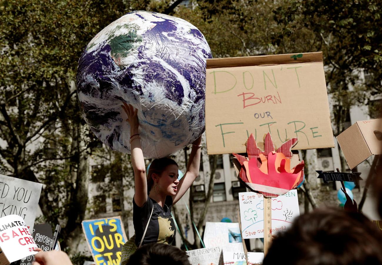 Mientras una manifestante sostiene una enorme pelota que emula el globo terráqueo, el resto de participantes en la protesta sostiene pancartas, en Manhattan, Nueva York (EE.UU.).. 