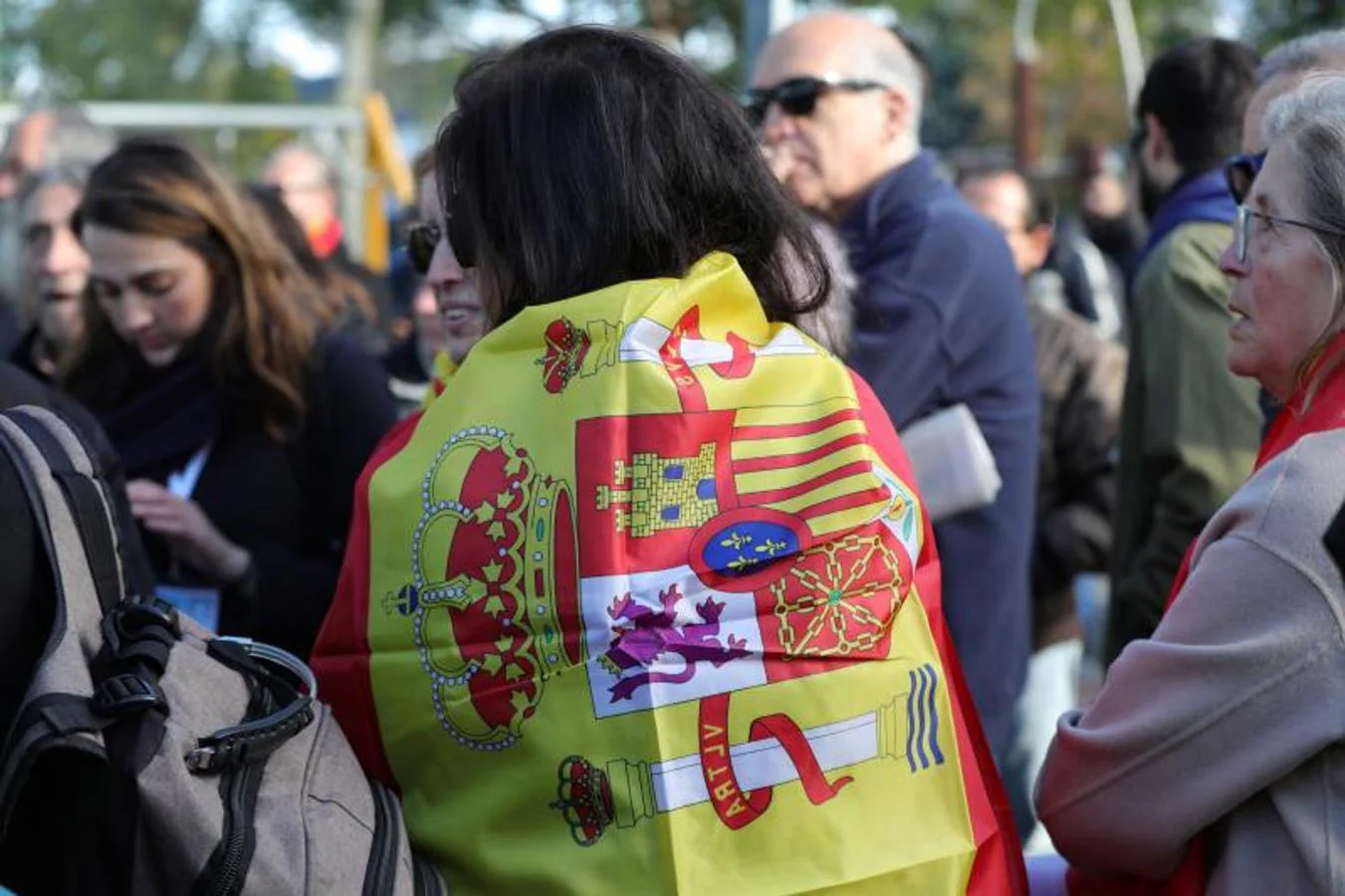 Una mujer, que forma parte de una pequeña concentración de franquistas en las inmediaciones del cementerio de El Pardo-Mingorrubio, se arropa con la bandera de España, antes de la inhumación de los restos de Francisco Franco en El Pardo.. 