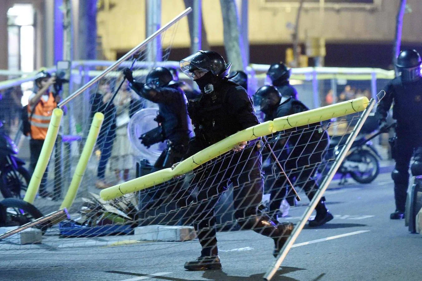 Los mossos retiran las vallas que los radicales les lanzaron durante las protestas. 