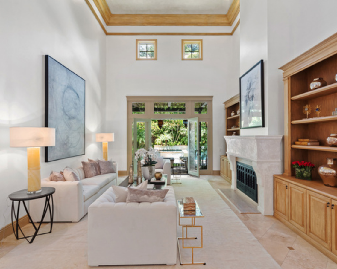 La mansión de Beverly Hills de Britney Spears. Como un segundo comedor está esta zona con sofás y acceso directo al jardín. Destacan sus lámparas de mesa, decoración recurrente en toda la mansión, y sus muebles de madera. La casa puede presumir también de sus altos techos.