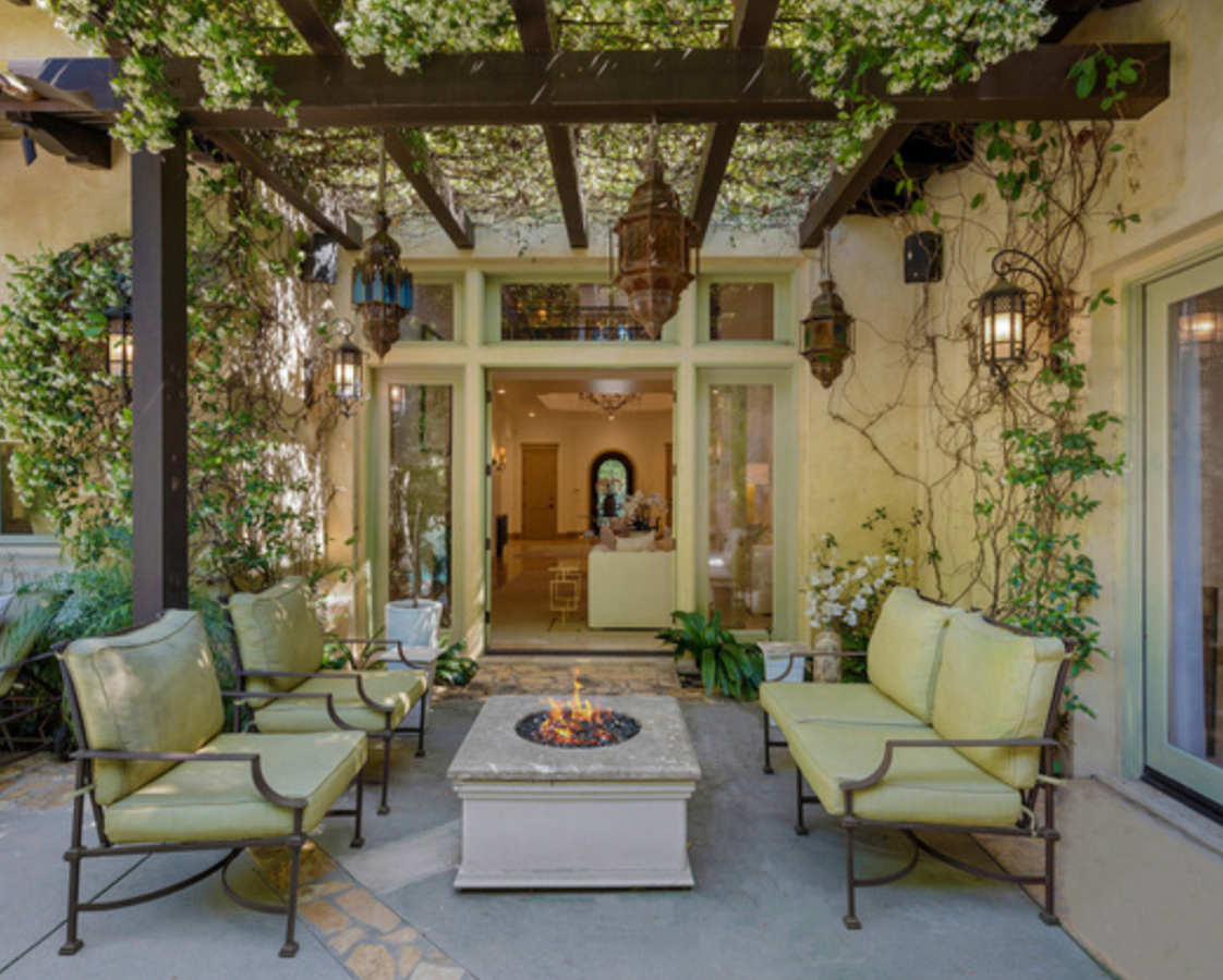 La mansión de Beverly Hills de Britney Spears. En el exterior se encuentra, también, esta zona con sillas y chimenea rodeada de plantas en la que sentarse a leer un libro al calor del fuego o conversar con amigos.
