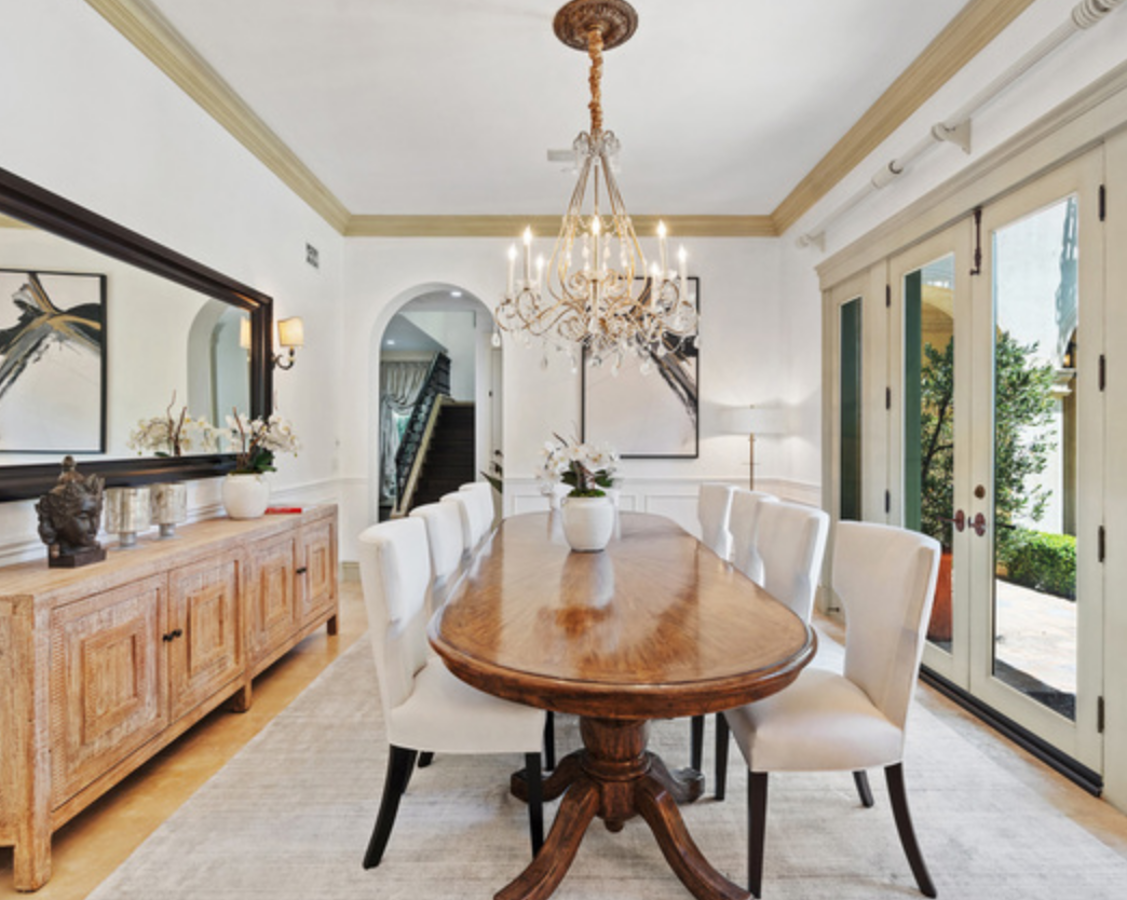 La mansión de Beverly Hills de Britney Spears. La mansión dispone de varias zonas de comedor como esta, situada en la planta baja y con acceso directo al jardín, en la que una mesa de madera ovalada preside la sala. A su alrededor, ocho sillas tapizadas en beis y un gran aparador de madera completan el mobiliario.