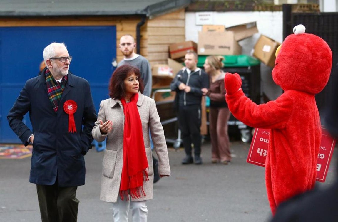 El líder laborista, Jeremy Corbyn, acude a la cita con su esposa luciendo el color del partido. A la derecha, un muñeco de una serie infantil. 