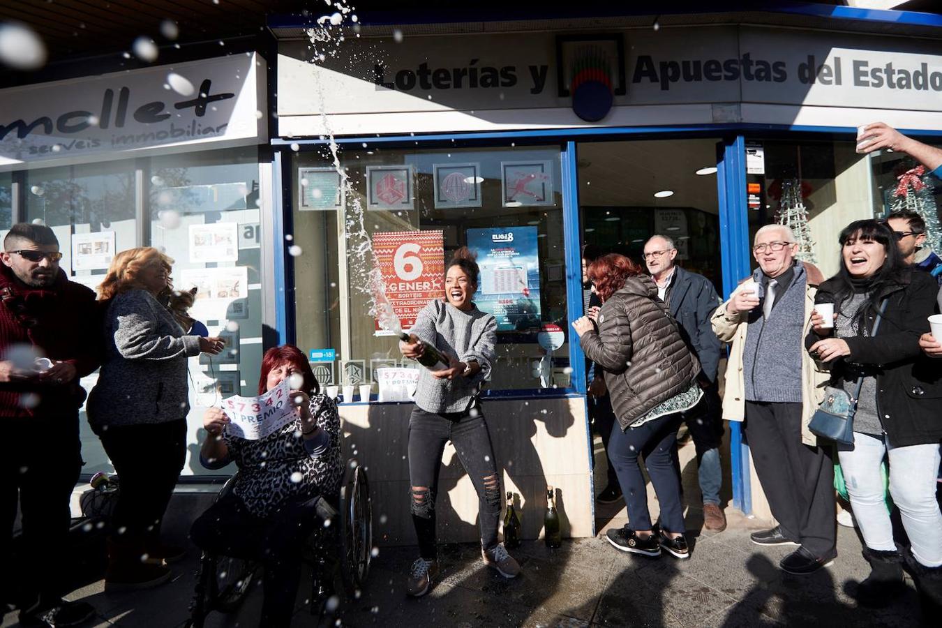 Varias personas festejan el Primer Premio del Sorteo Extraordinario del Niño en la puerta de la administración de Lotería de Mollet del Vallés. 