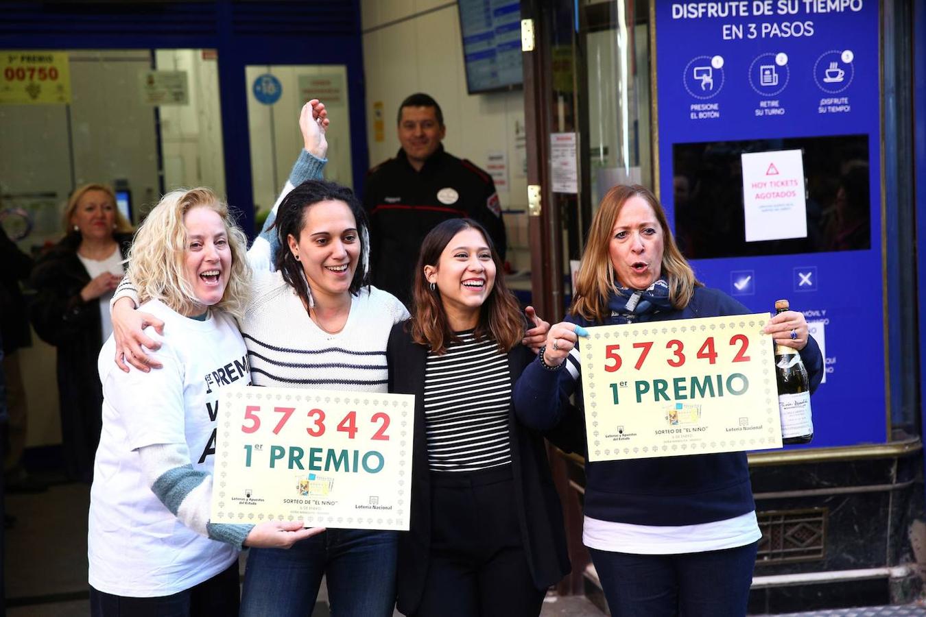 Un grupo de personas celebra en la administración de Lotería Doña Manolita haber dado parte del Primer Premio del Sorteo del Niño. 