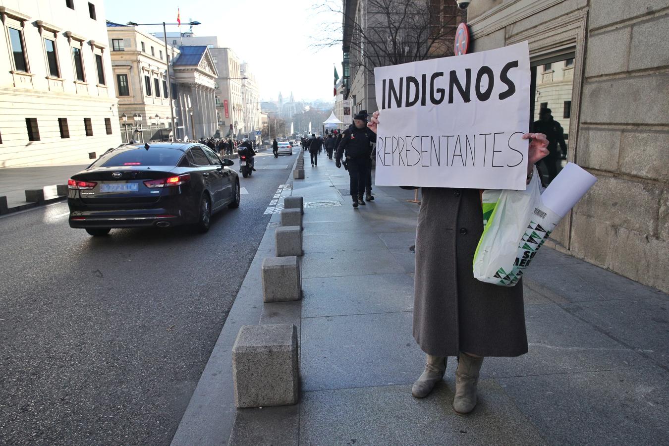 Una mujer sujeta un cartel en el que se lee «Indignos representantes» junto al Congreso de los Diputados. 