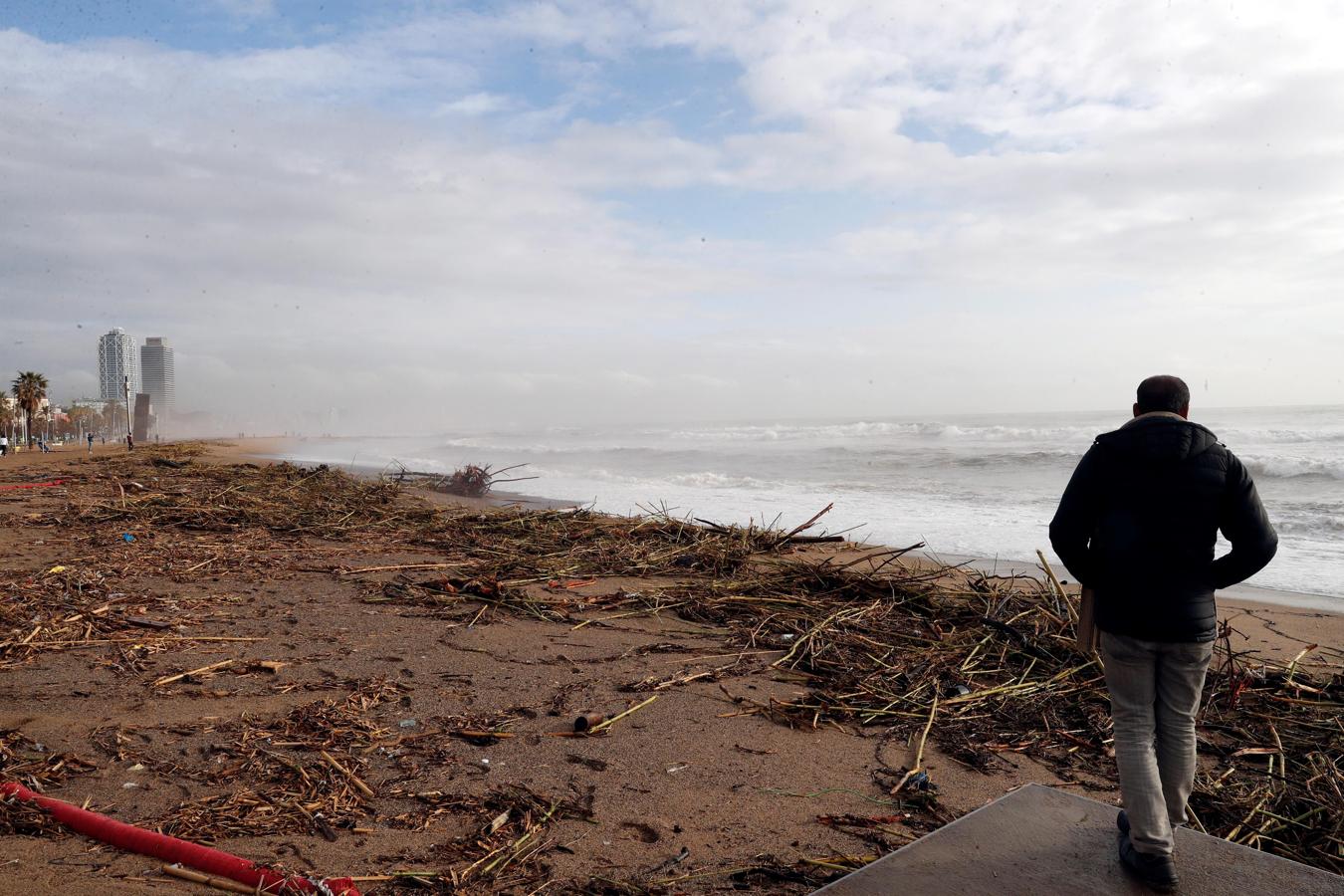 Un hombre observa los daños causados en la playa de la Barceloneta