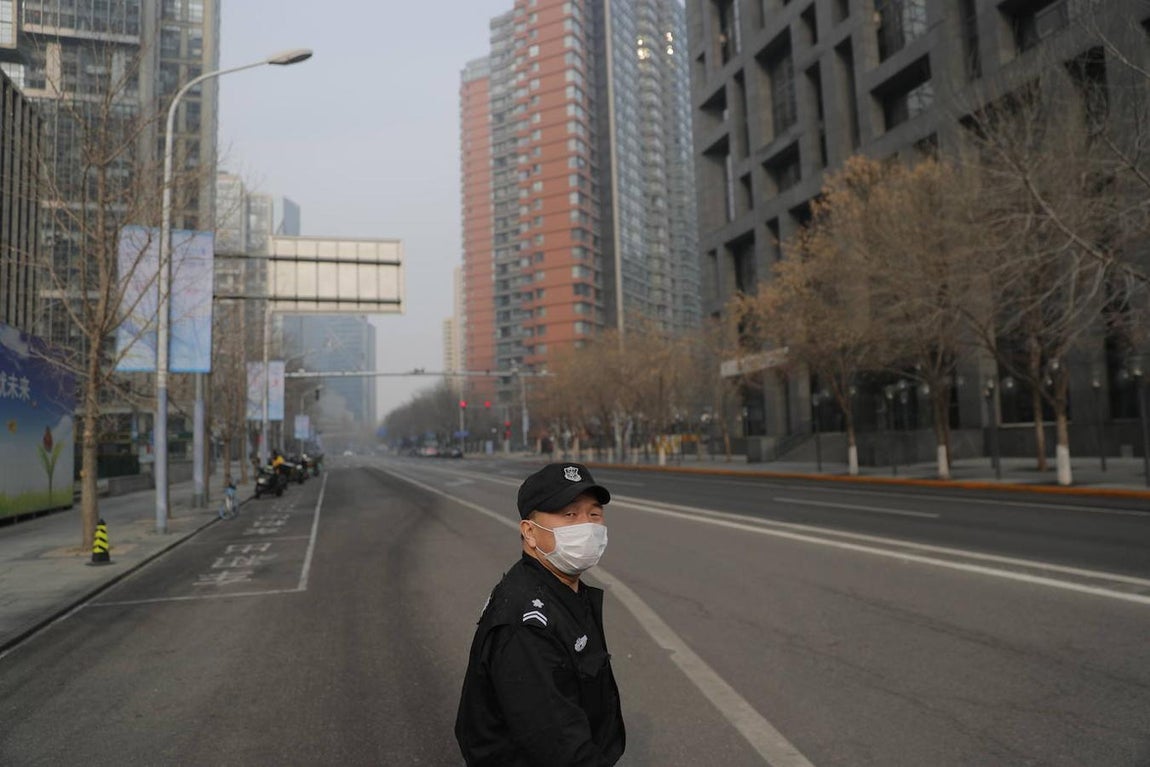 Un guardia de seguridad con mascarilla vigila una calle vacía en Pekín. 