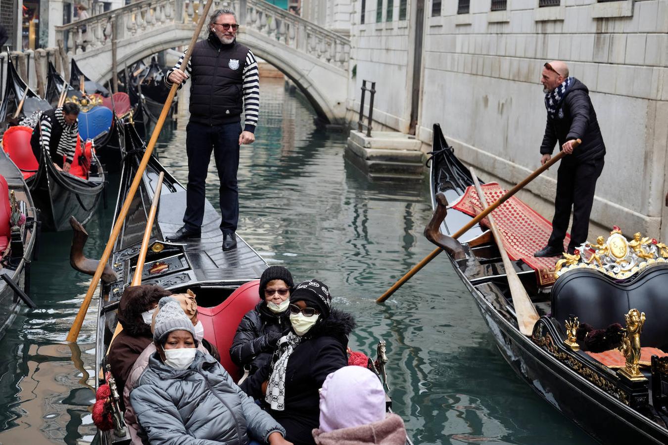 Un grupo de personas con mascarilla pasean en góndola por un canal de la ciudad. 