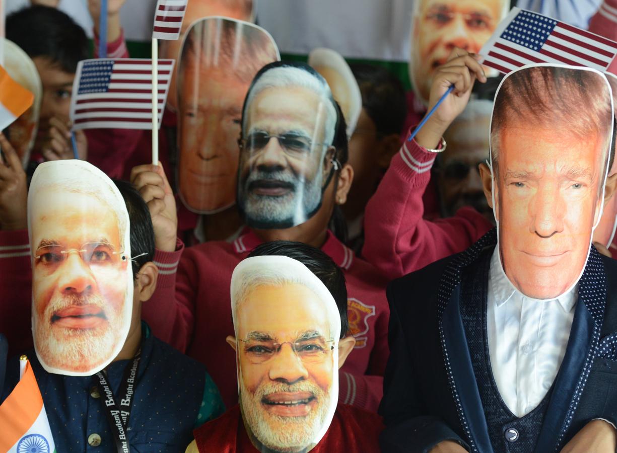 Estudiantes con máscaras del primer ministro indio y el presidente estadounidense posan para una foto en la escuela Bright Academy en Siliguri. 