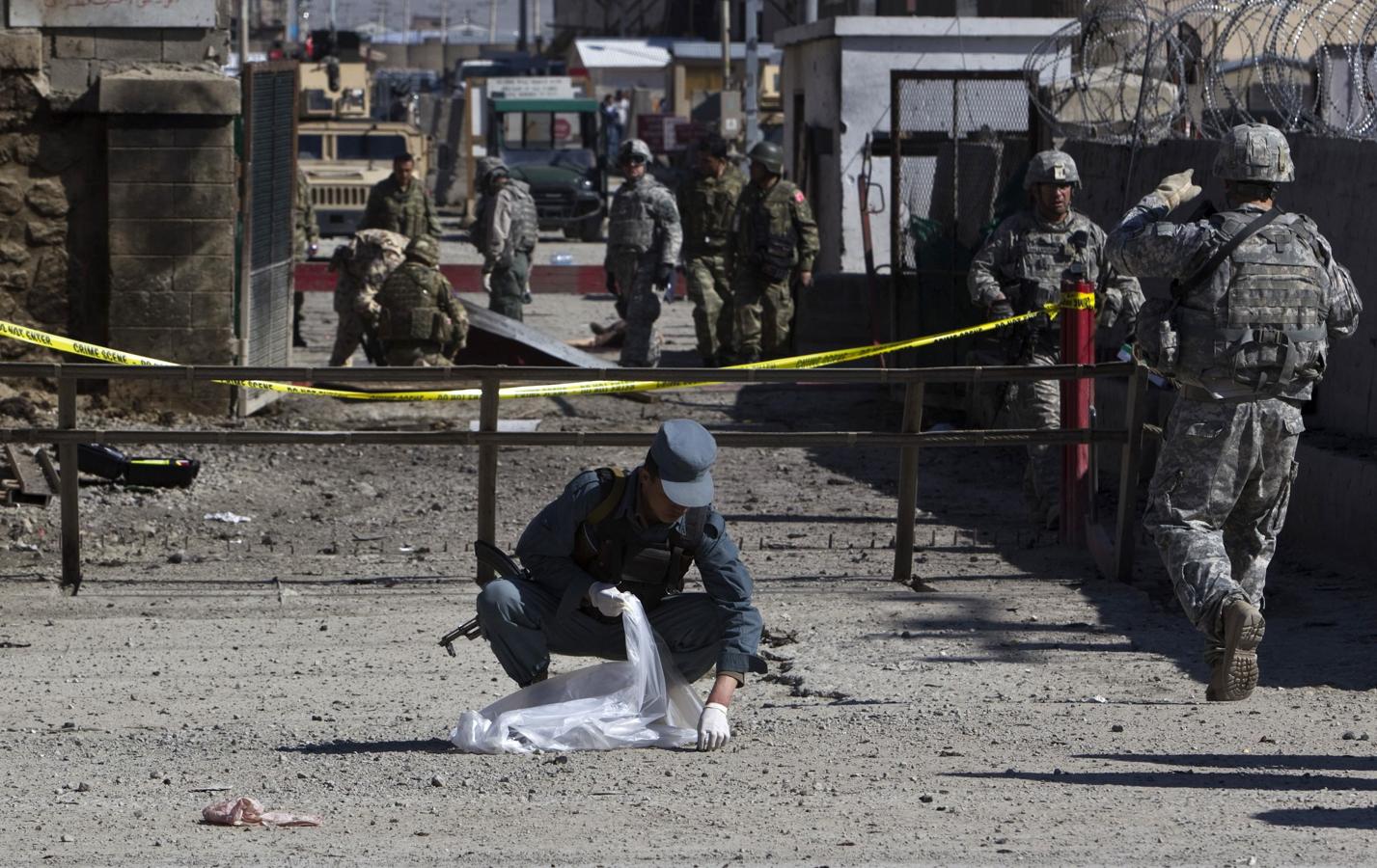 Un policía afgano recoge los restos de un cuerpo tras un ataque de los opositores cerca de una base de coches en Kabul