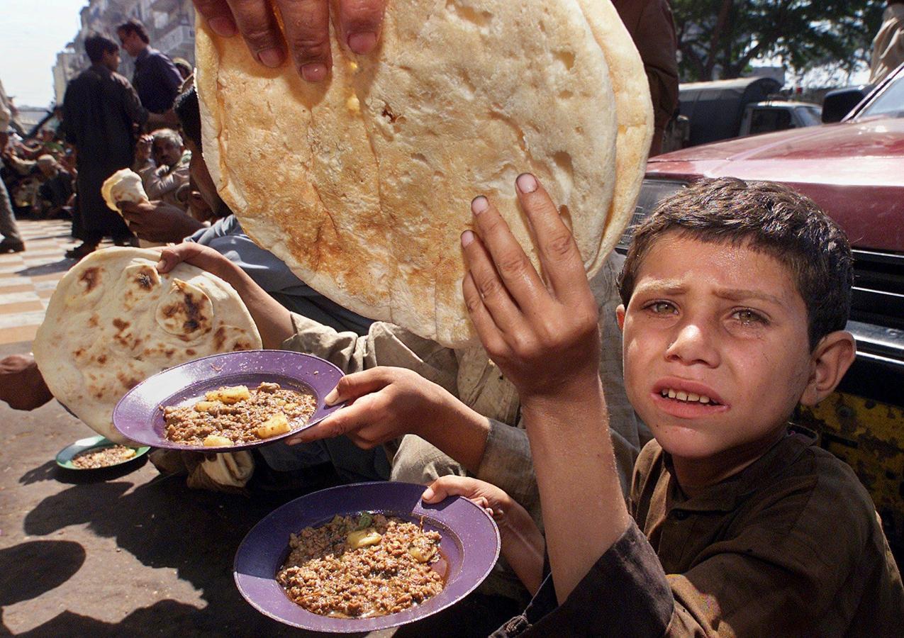 Un menor que trabaja recogiendo la basura, con los ojos llorosos, recibe un plato de comida