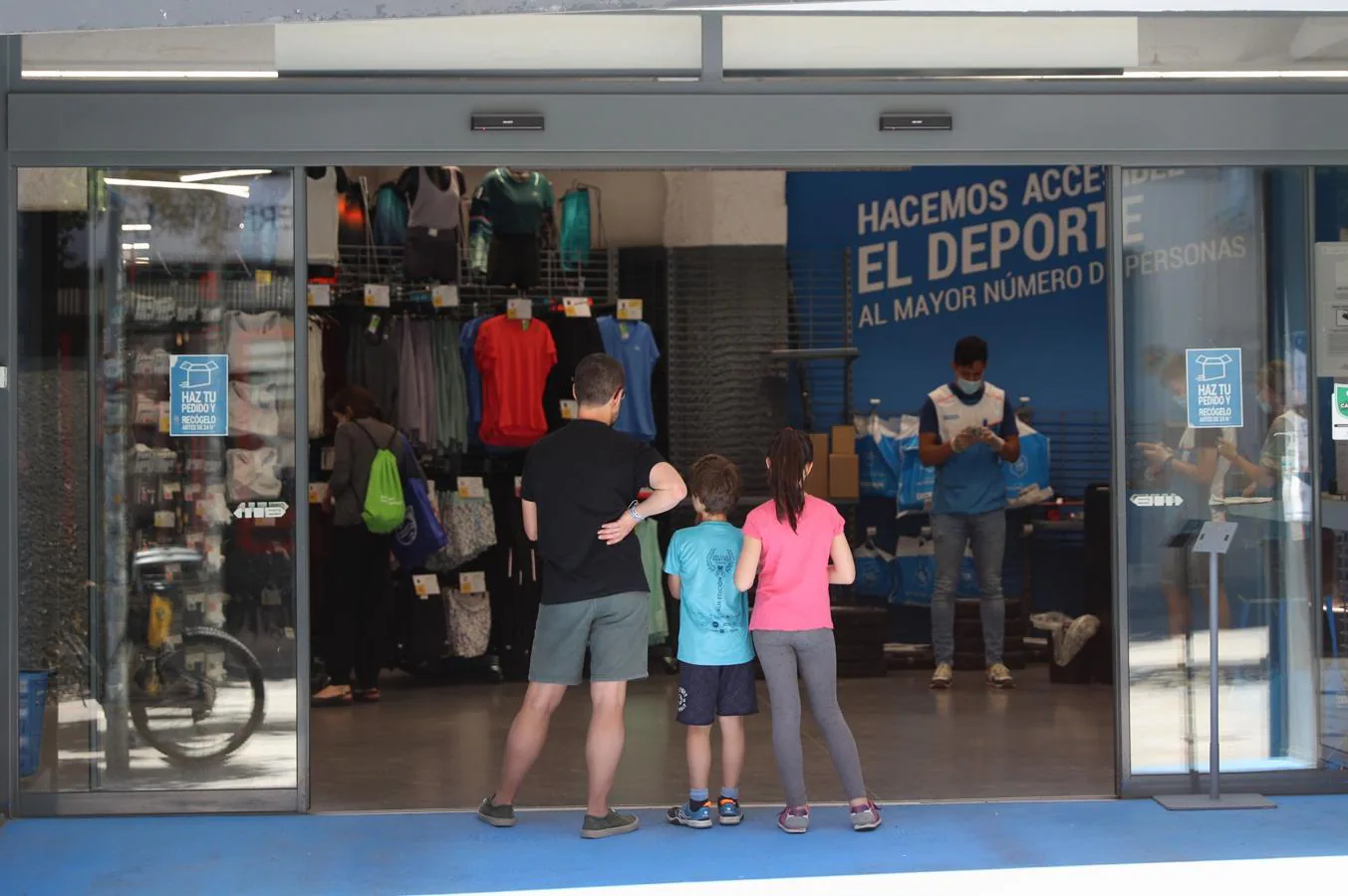 Prohibidas las aglomeraciones. Una familia aguarda su turno en la puerta de un local de deportes en Madrid, que está en la fase 0