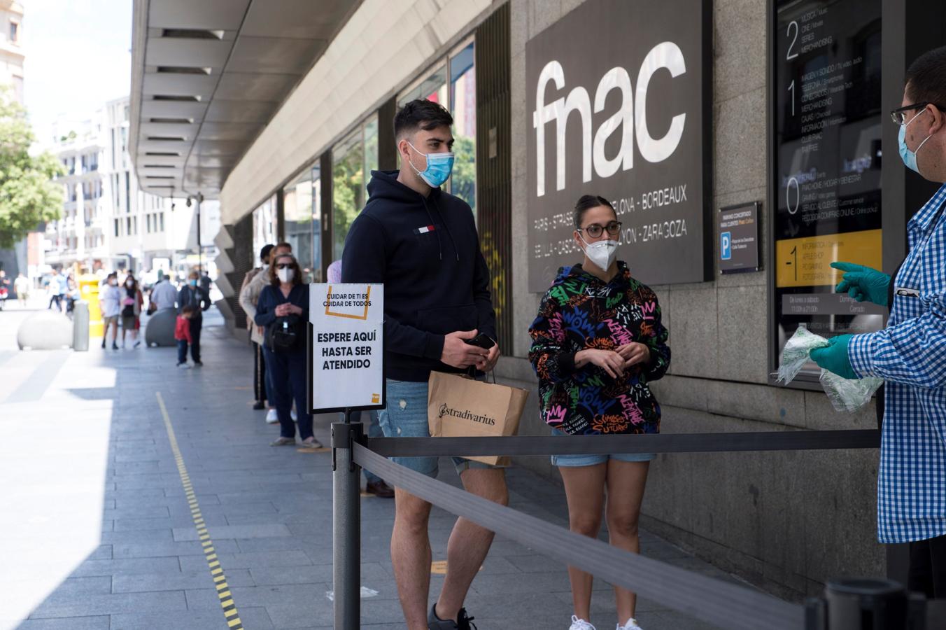 De compras... guardando la cola. Es la nueva realidad. Guardar cola para todo. Hoy en Madrid, como en todas las zonas que inauguran la fase 2, había ganas de comprar. Arriba, fila a las puertas de la FNAC de Callao