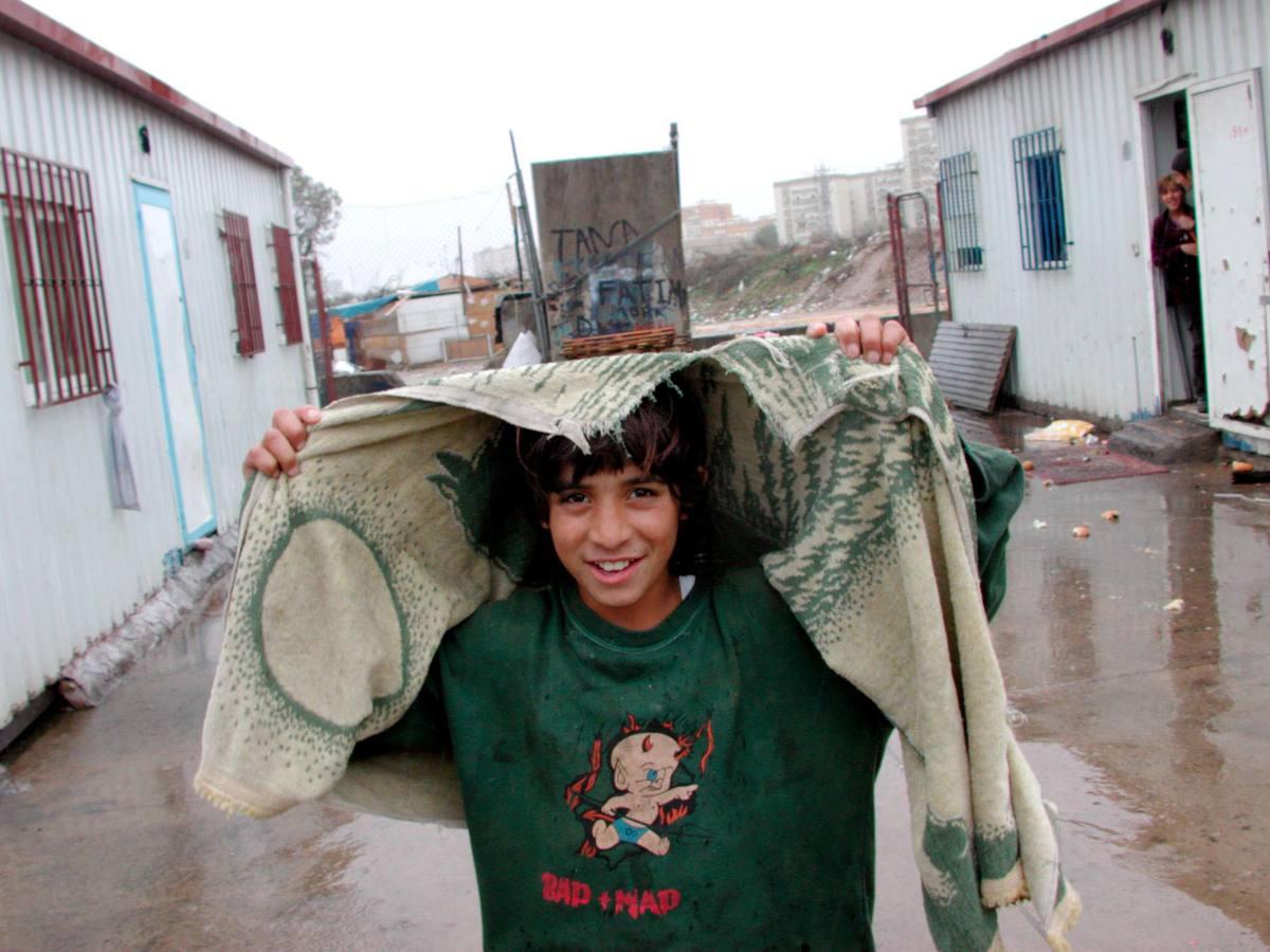 Un niño se cubre de la lluvia con una prenda roñosa