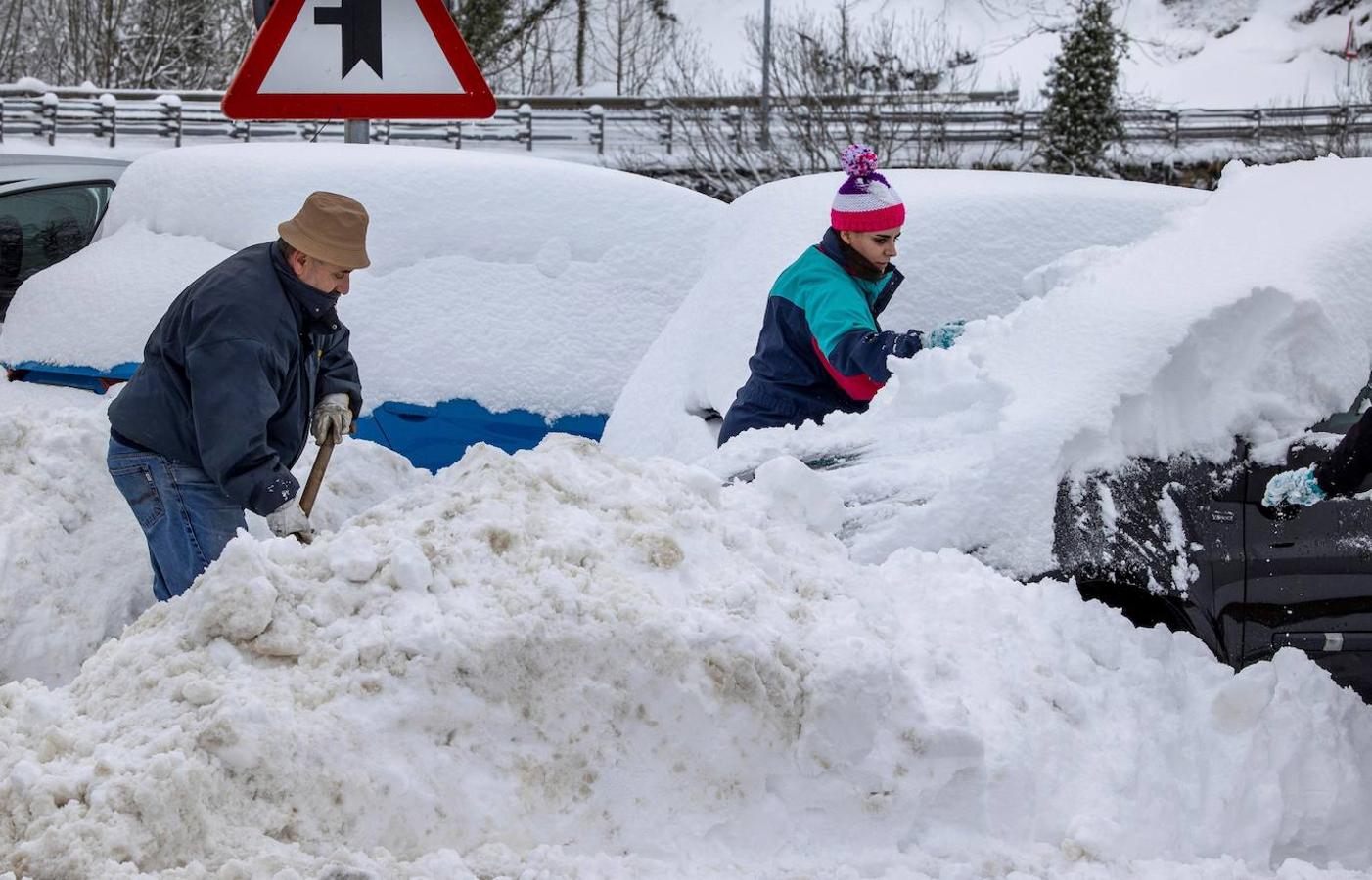 La autopista del Huerna (AP-66), principal vía de comunicación entre Asturias y León, está ya reabierta al tránsito de camiones tras las intensas nevadas de las últimas horas. En la imagen, unos vecinas tratan de quitar la nieve de sus vehiculos en el pueblo de Pajares. 