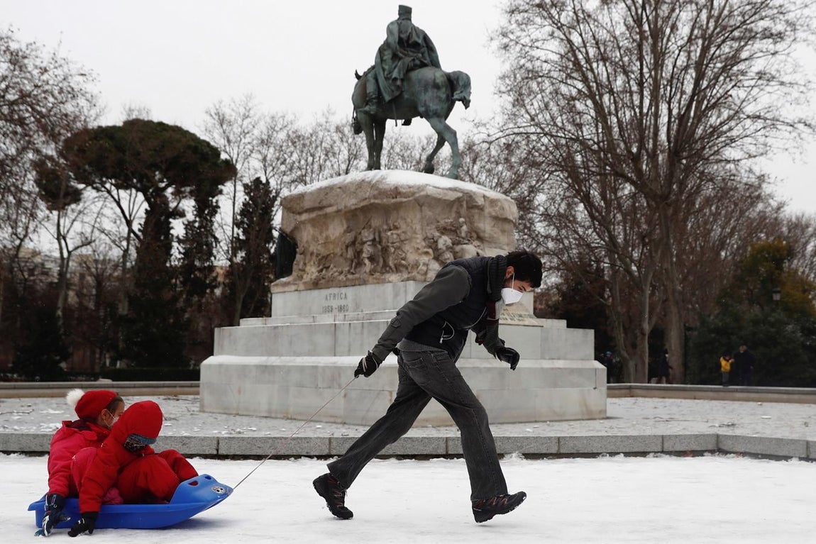 El Retiro, blanco. Un hombre tira de un trineo con dos niños, este viernes, en el parque del Retiro, que está cubierto de nieve desde el jueves.