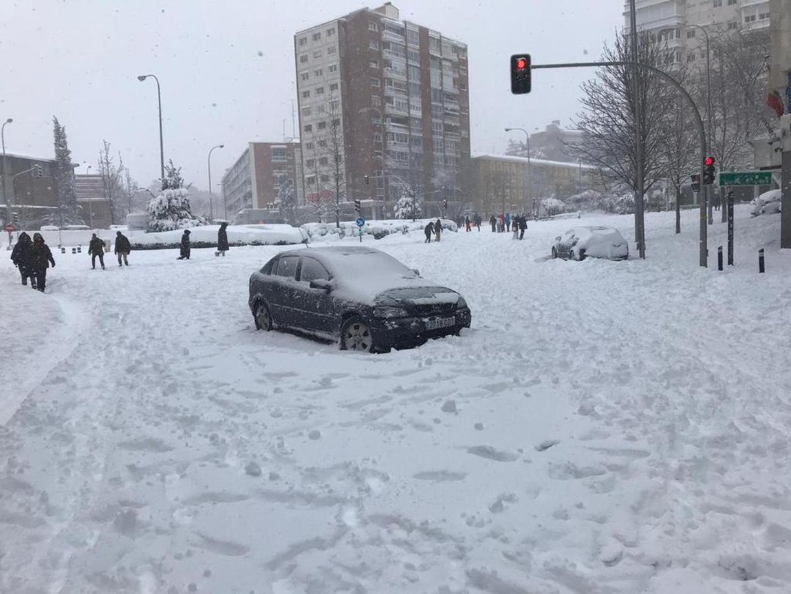 Un coche abandonado en Padre Damián. Un coche abandonado en mitad de la calle del Padre Damián preside la carretera invisible bajo la nieve. Grupos de personas juegan en los alrededores del estadio Santiago Bernabéu.