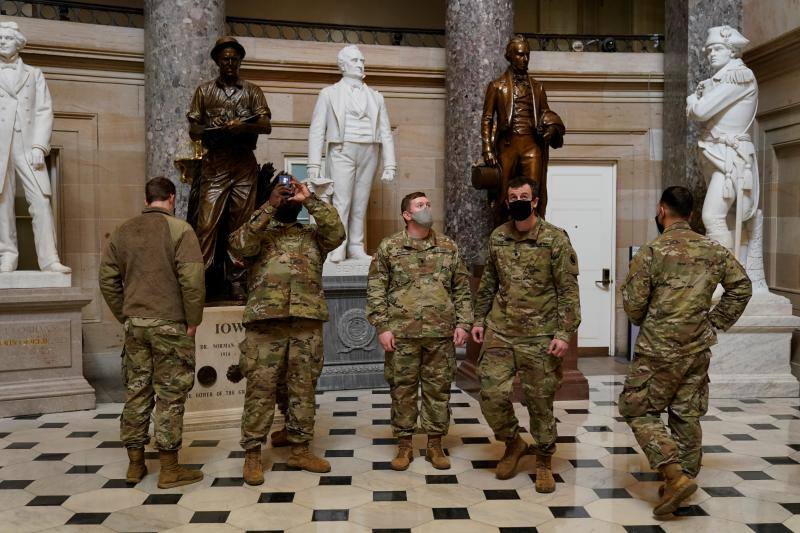 Soldados caminan y toman fotos del Capitolio, a la espera de que concluya la votación de «impeachment» a Trump.. 