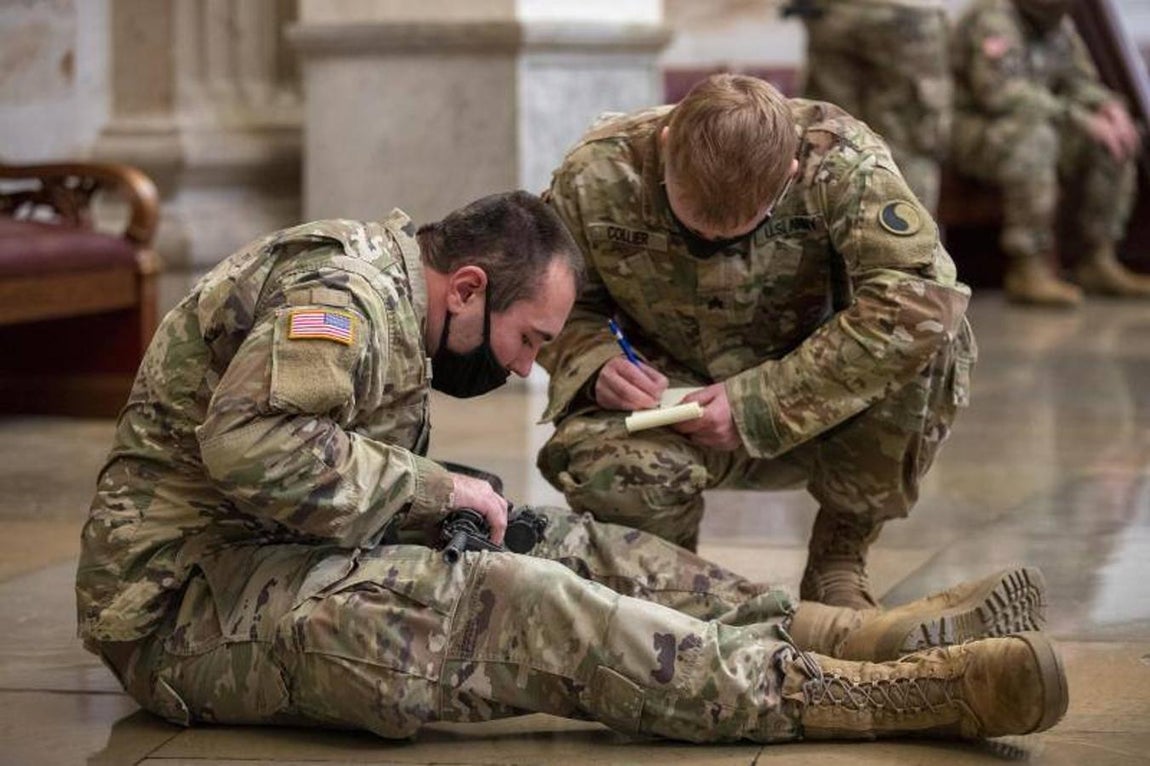 Dos soldados apuntan el número de serie de un rifle.. 