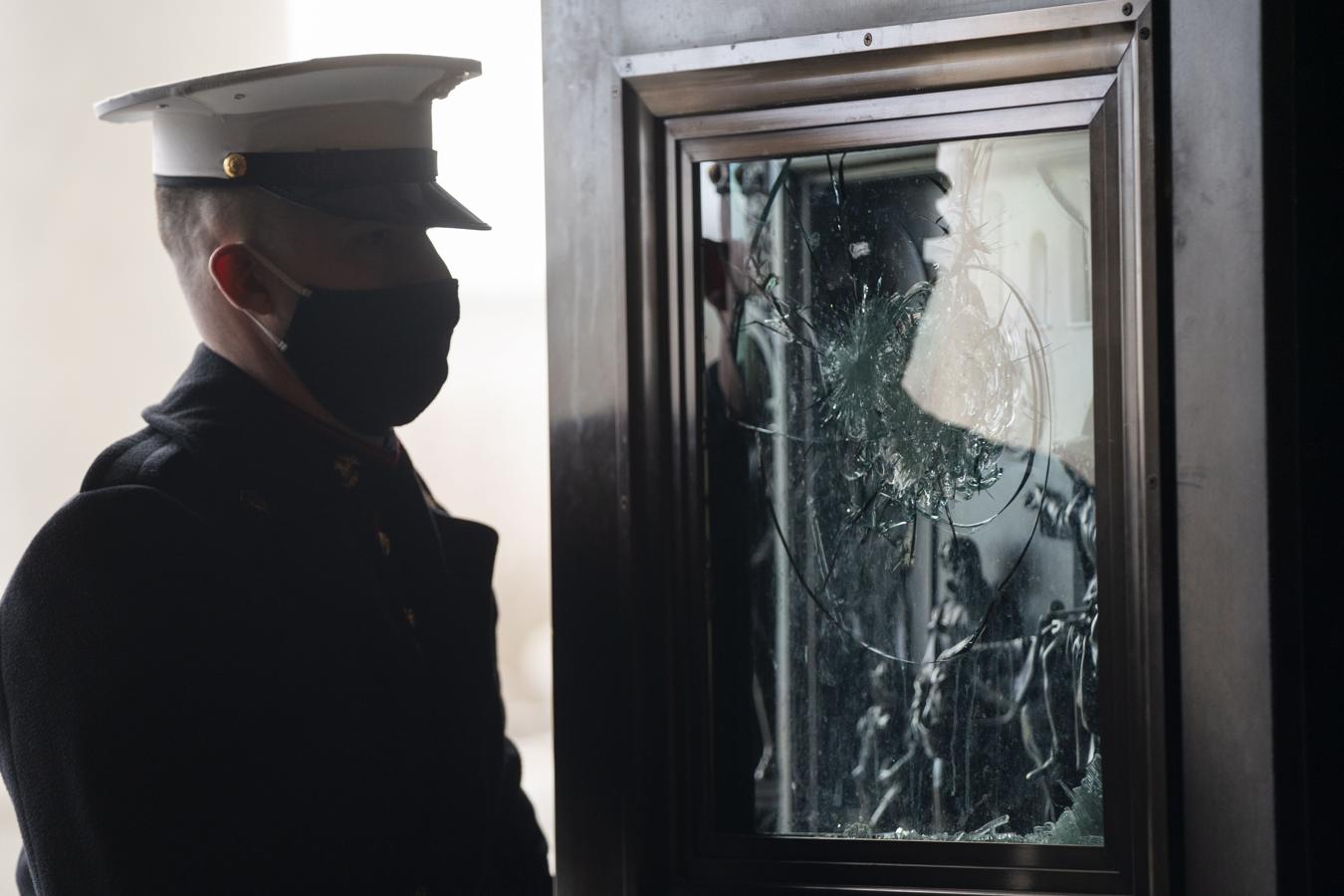 Un marine observa una ventana destrozada por los insurgentes durante el asalto al Capitolio. 