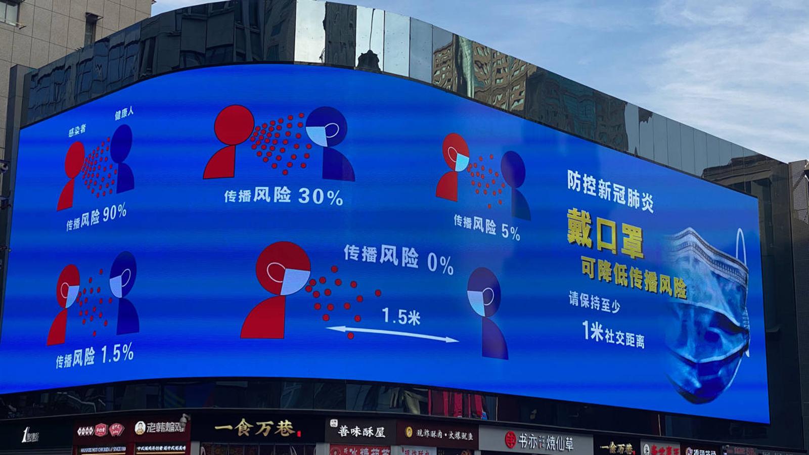 En una gran pantalla en el centro de Wuhan, un anuncio recuerda la necesidad de llevar mascarillas y mantener la distancia para impedir la propagación del coronavirus. 