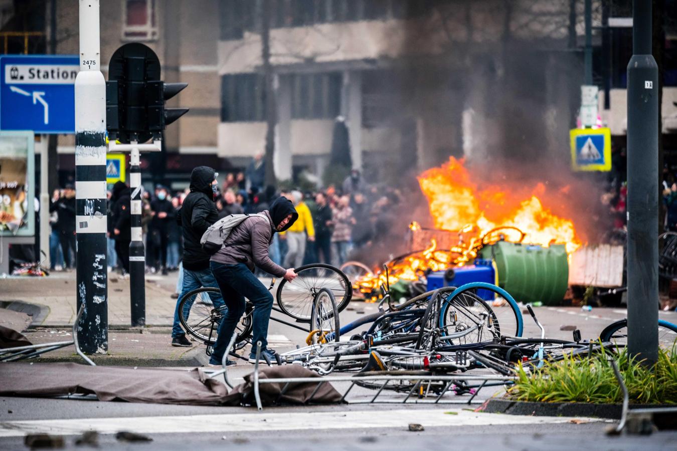 Un hombre lanza una bicicleta al suelo. Al fondo, los manifestantes prendieron fuego a varias bicis y contenedores de basura. 