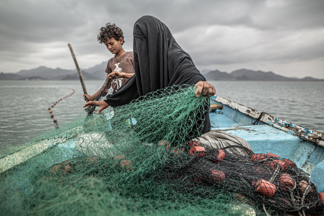 (Fotografía individual nominada en 'Temas contemporáneos') Fátima y su hijo preparan una red de pesca en un barco en la bahía de Khor Omeira, Yemen, el 12 de febrero. 